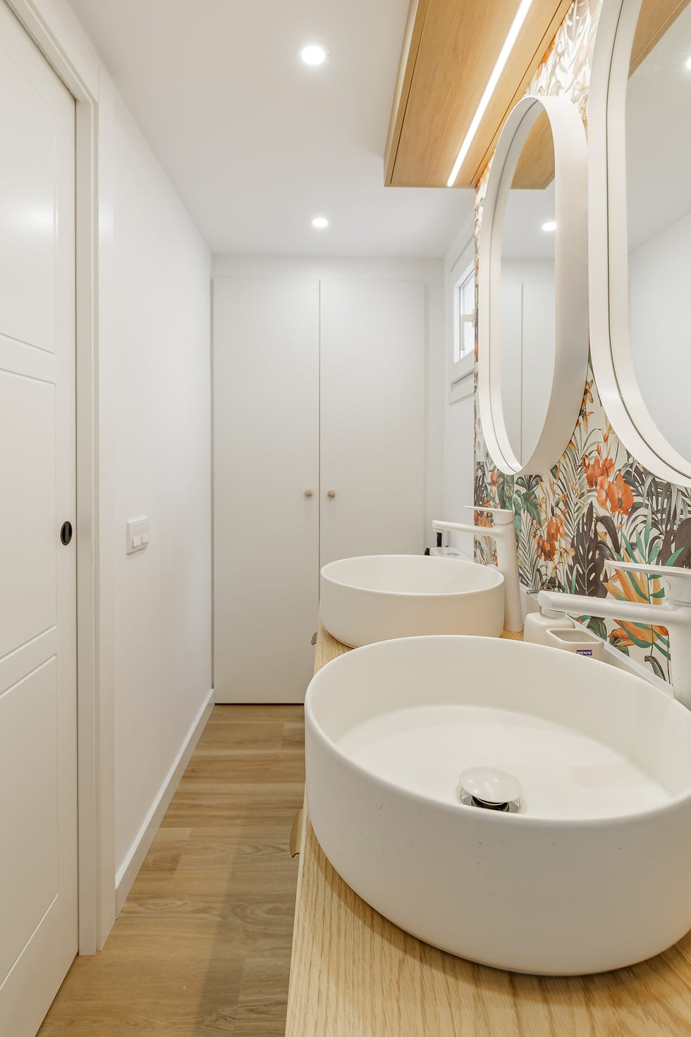baño con papel pintado con motivos exóticos y armario blanco
