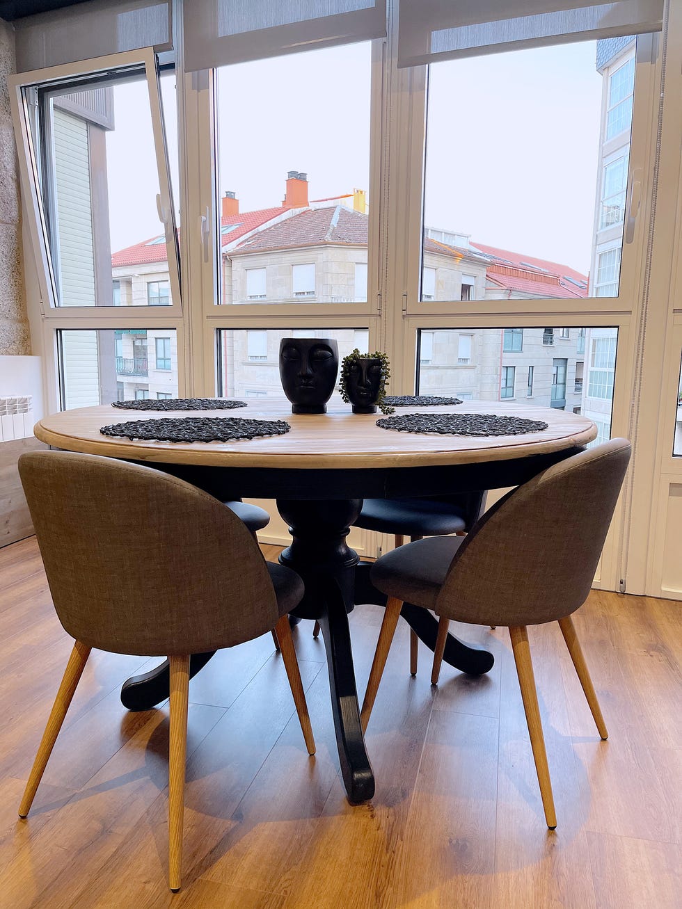 comedor con mesa rústica redonda y sillas modernas tapizadas en gris