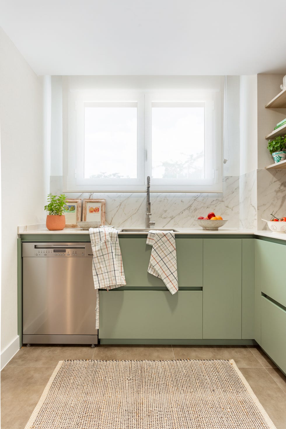 cocina con frentes verdes y encimera y salpicadero efecto mármol