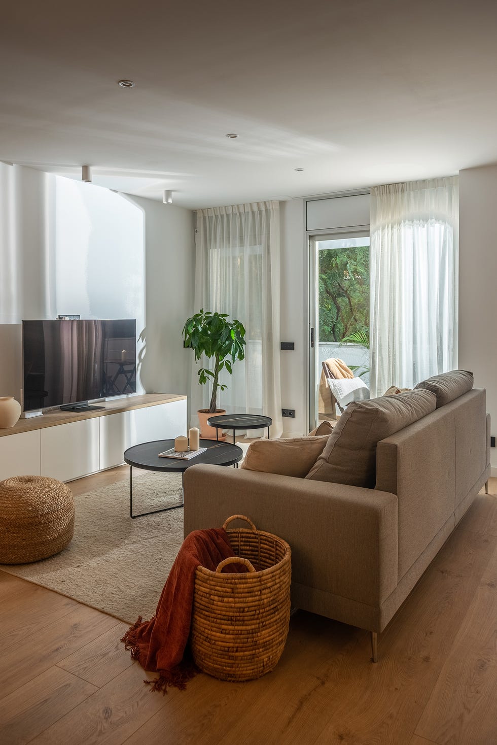 salón con sofá gris y mesas de centro redondas y mueble de tv blanco