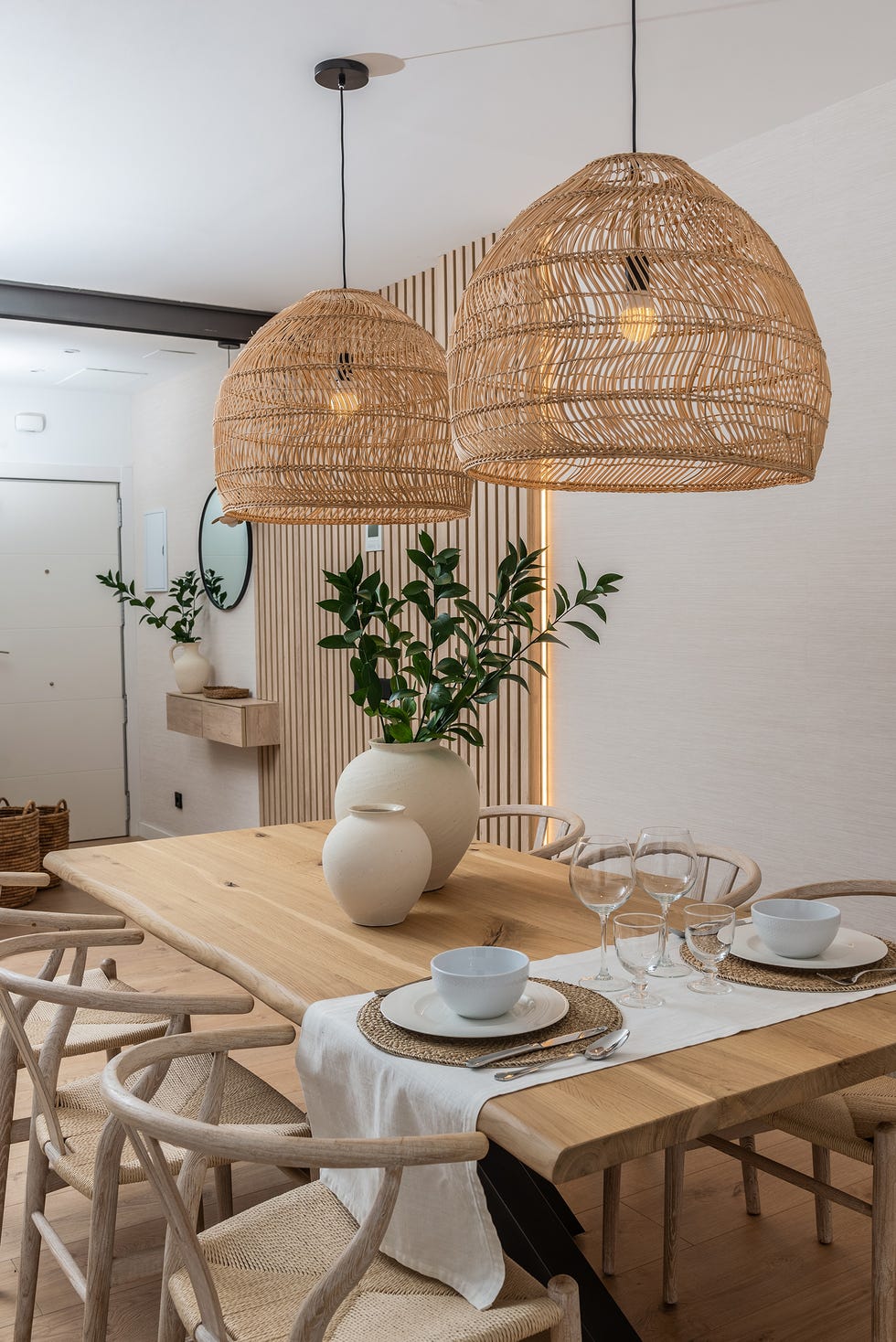 mesa de comedor de madera, sillas wishbone y lámpara de fibras