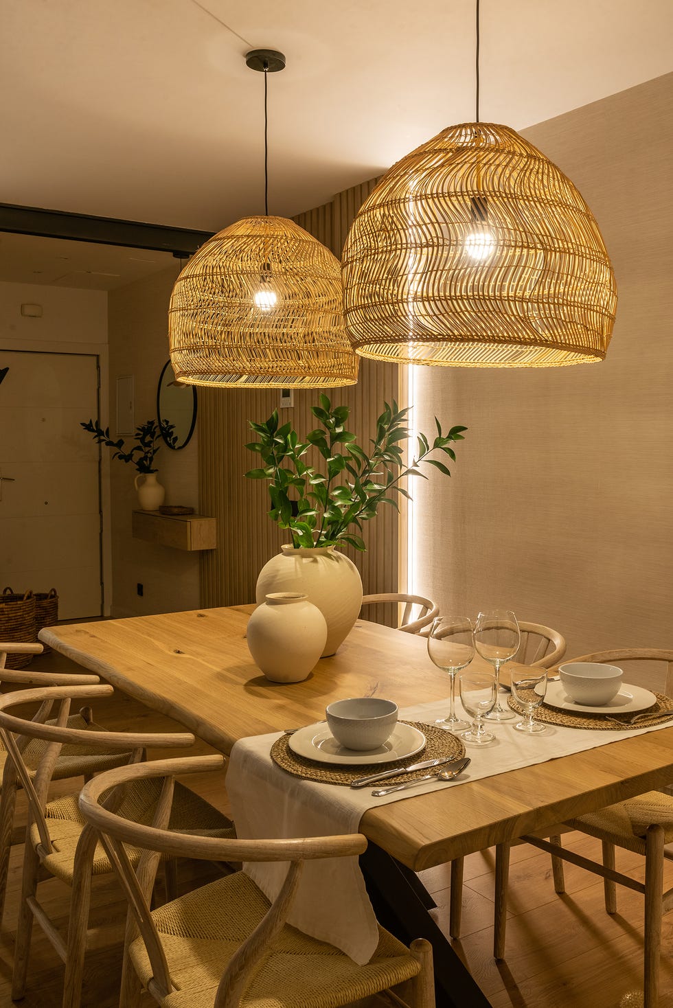 mesa de comedor de madera, sillas wishbone y lámpara de fibras