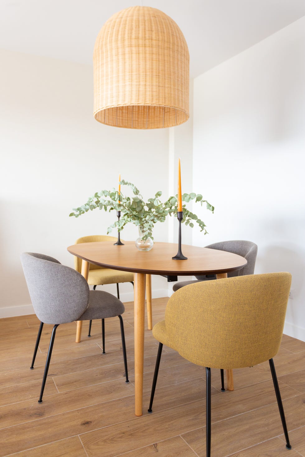 mesa de comedor de madera ovalada y sillas tapizadas en gris y mostaza
