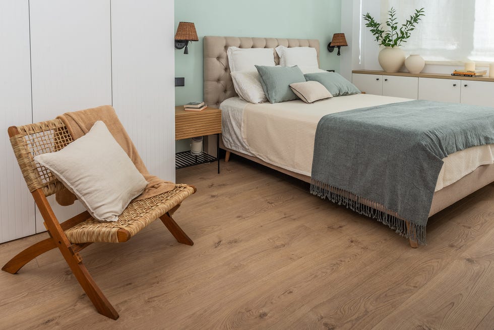 cama con cabecero acolchado beige y butaca de ratán