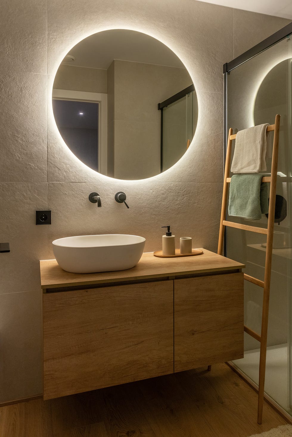baño con mueble de madera volado y espejo redondo