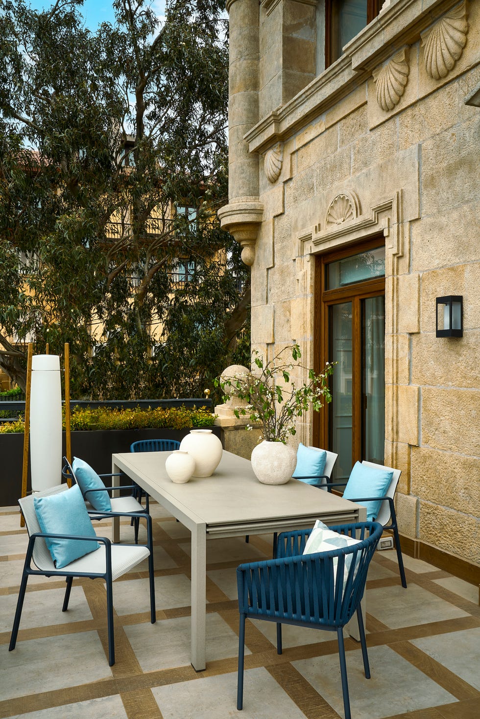 mesa de comedor exterior gris y sillas de cuerda azul