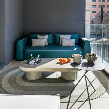 terraza con sofá azul y mesa de centro de hormigón