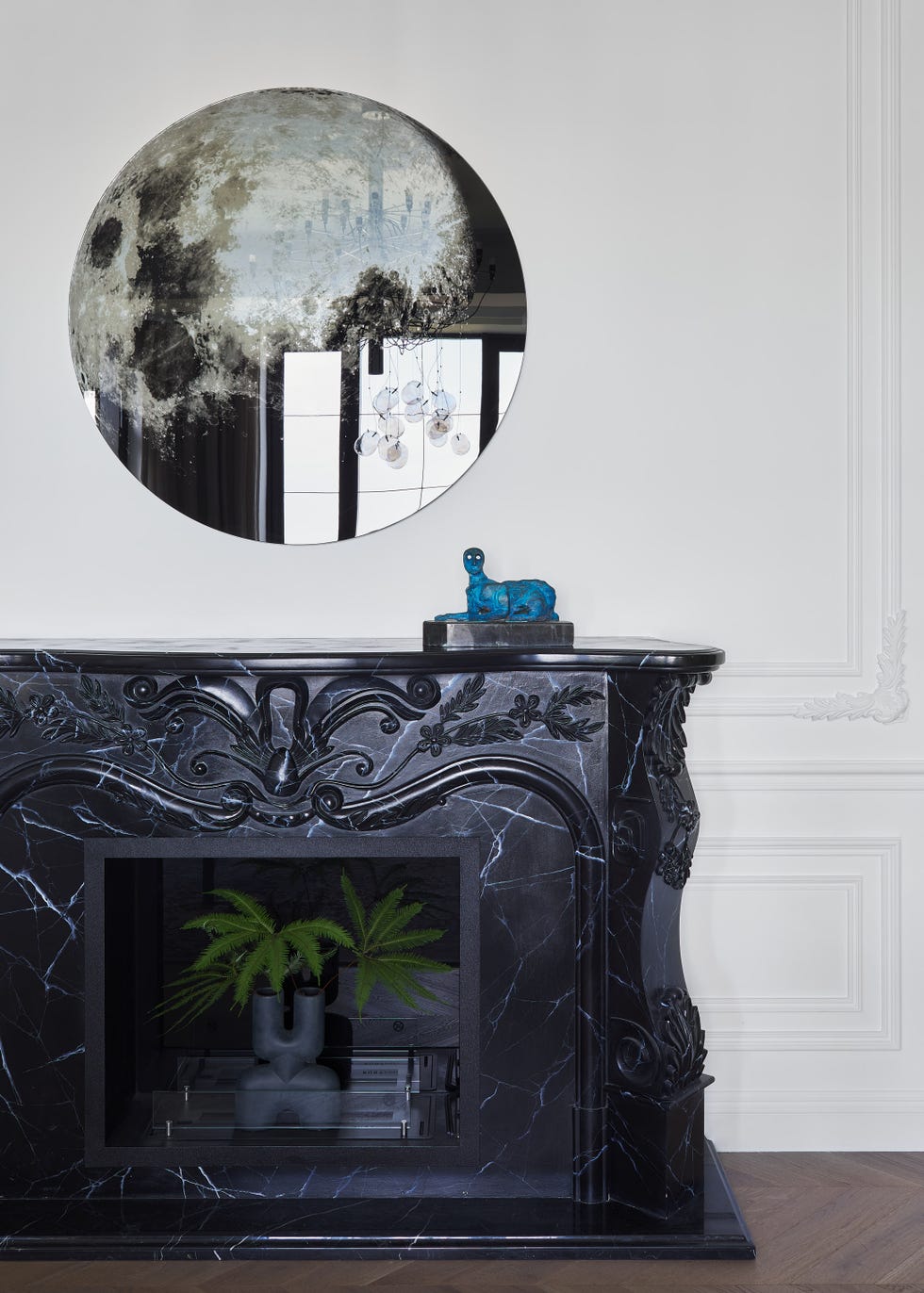salón con molduras decorativas y chimenea de mármol negro