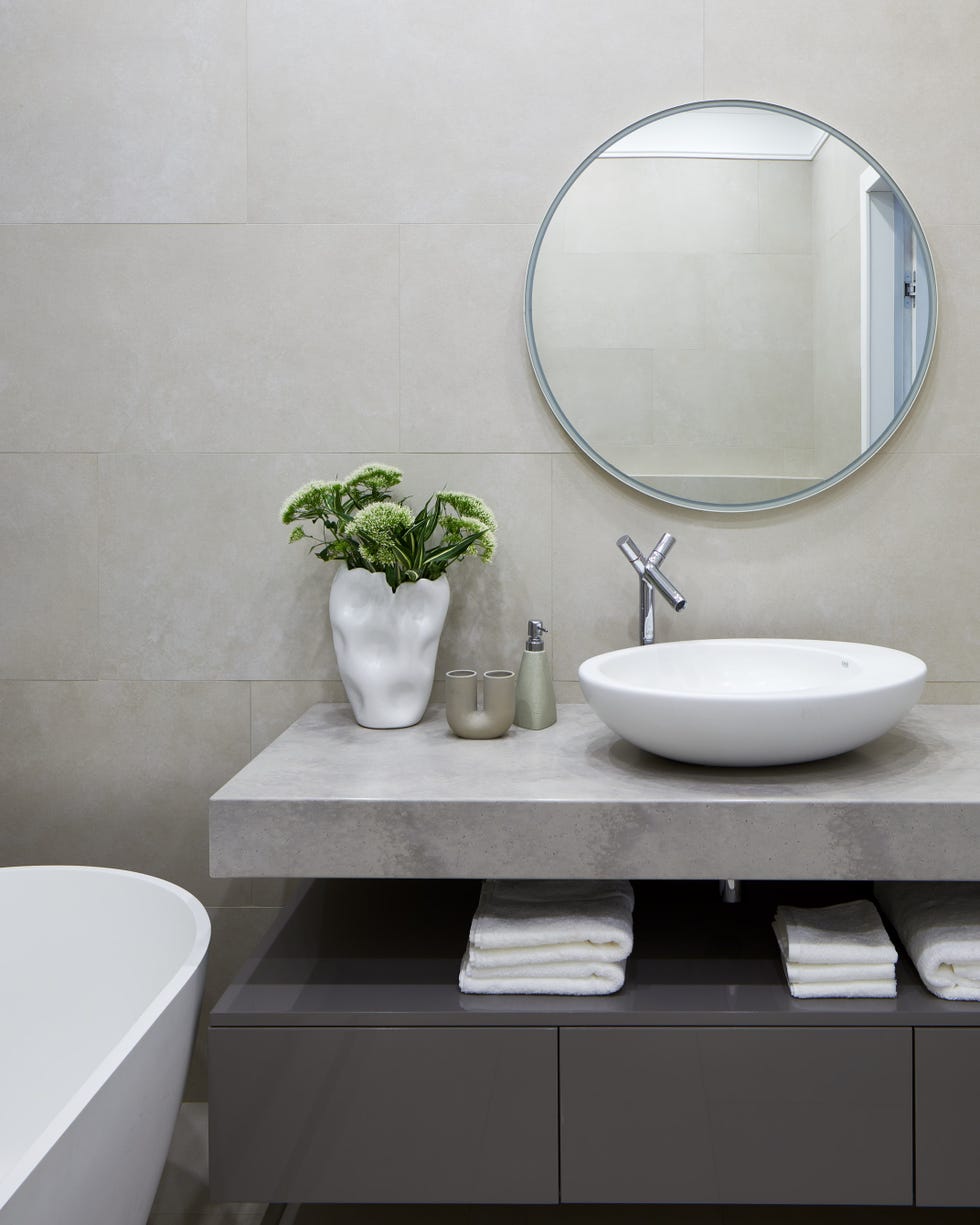 baño moderno con estante de mármol y mueble suspendido gris con almacenaje