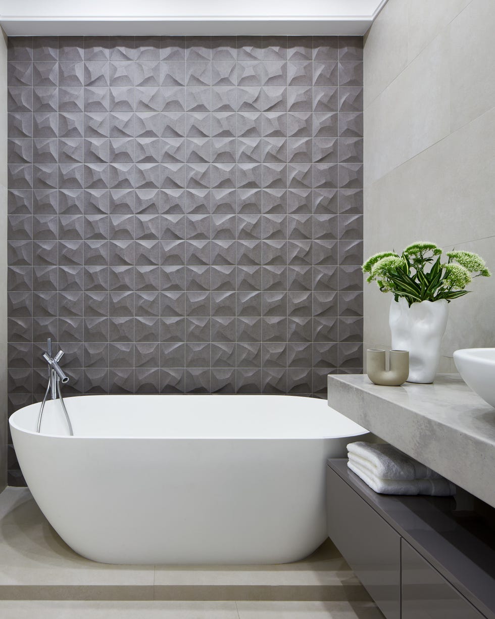baño con bañera exenta y pared con azulejos en 3d grises