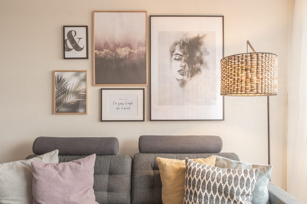 sofá gris y pared con láminas decorativas