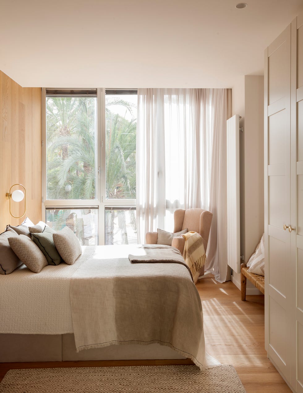 dormitorio con pared de madera en el cabecero y butaca orejera