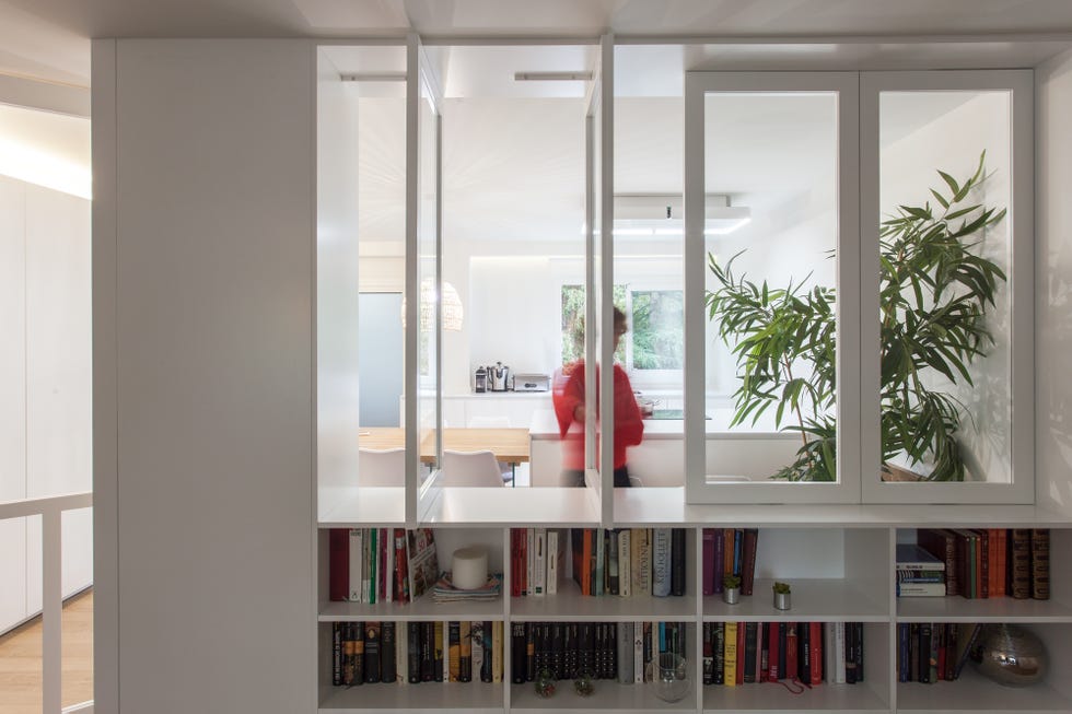biblioteca abierta a la cocina a través de unos ventanales