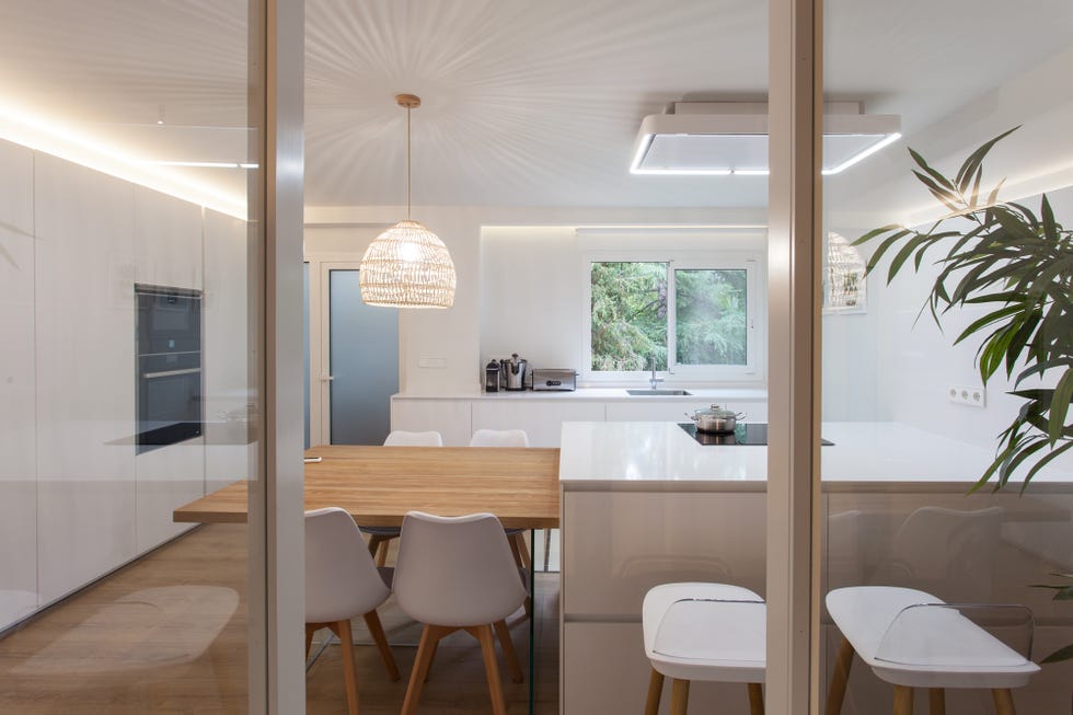 cocina con isla central blanca y mesa de comedor de madera integrada