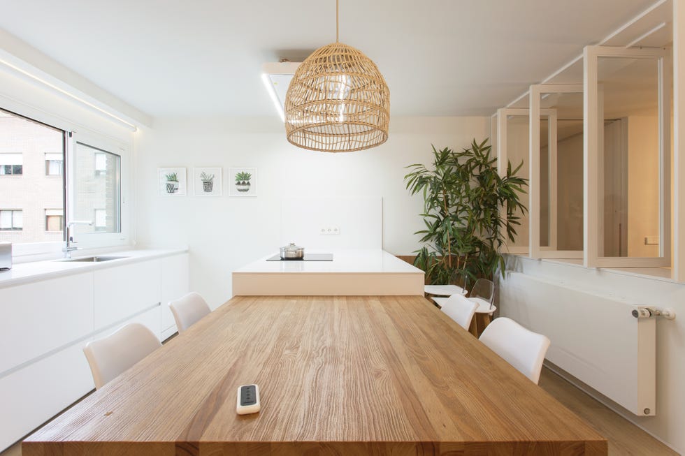 cocina con isla central blanca y mesa de comedor de madera integrada