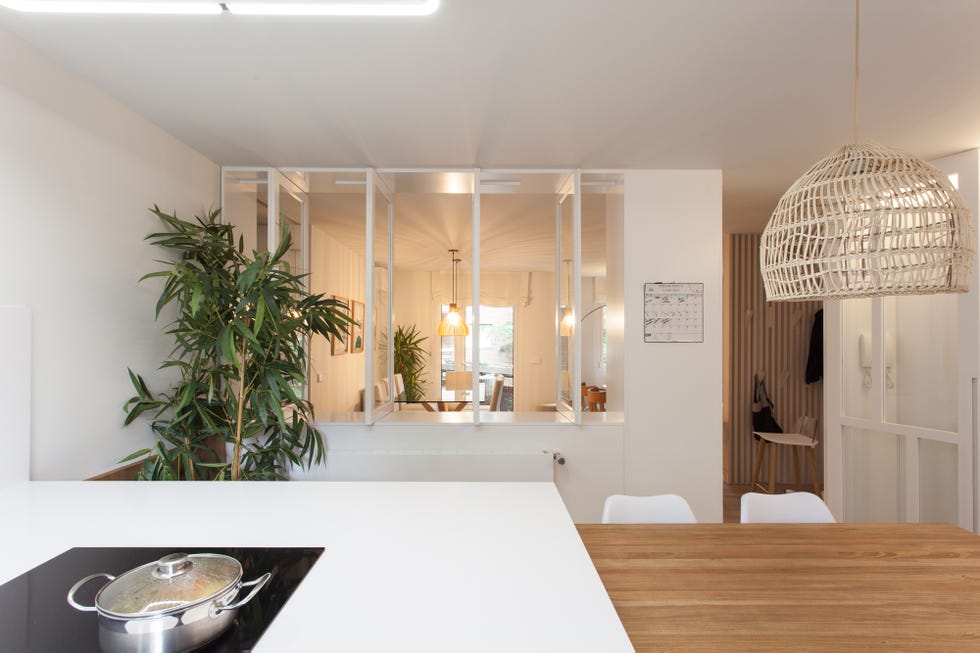 cocina con isla central blanca y mesa de comedor de madera integrada