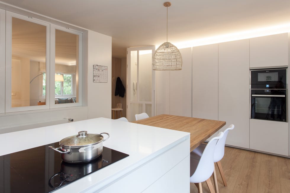 cocina con isla central blanca y mesa de comedor de madera integrada