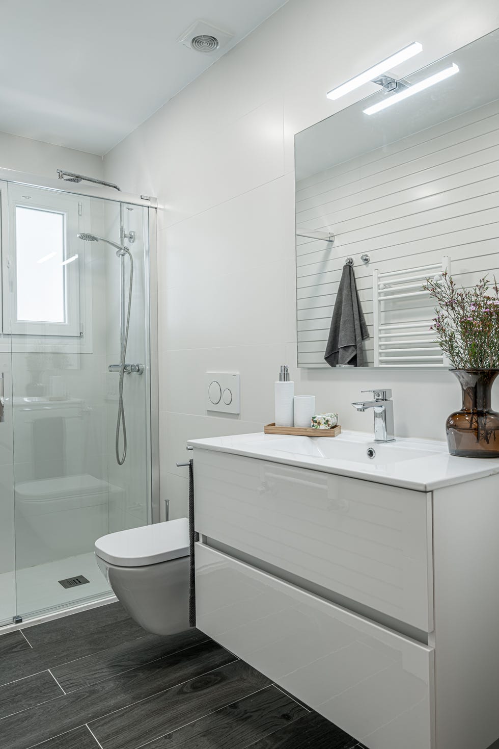 baño con ducha de obra y mueble suspendido con cajones sin tiradores en color blanco lacado