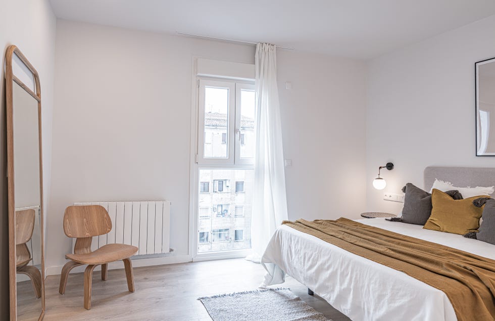 dormitorio de estilo minimalista decorado en blanco, gris y mostaza