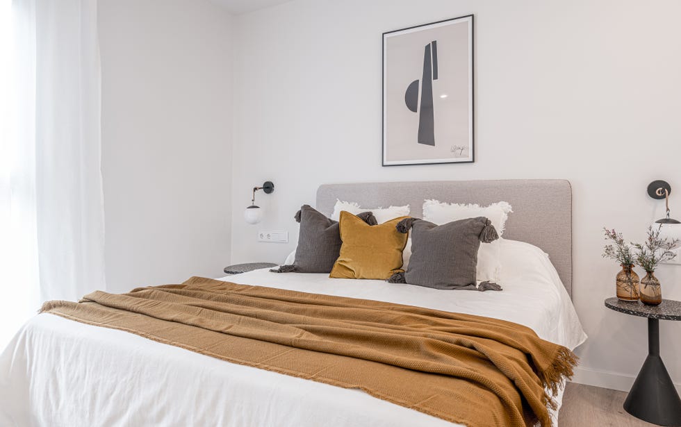 dormitorio de estilo minimalista decorado en blanco, gris y mostaza