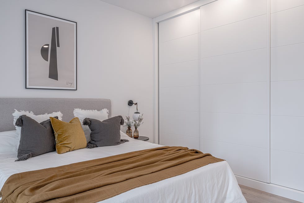 dormitorio de estilo minimalista decorado en blanco, gris y mostaza