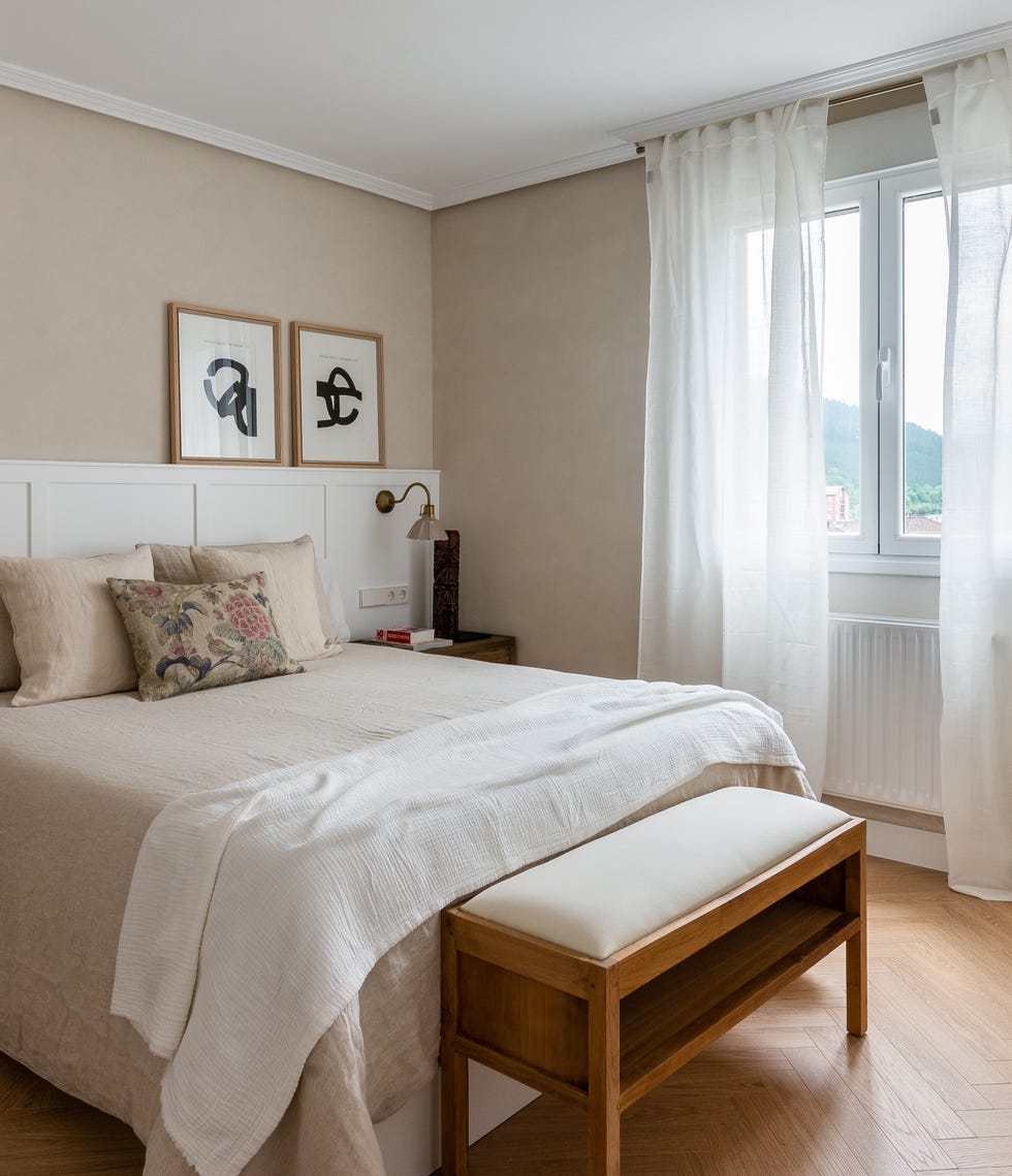 cama con cabecero blanco con molduras y banco a los pies de la cama