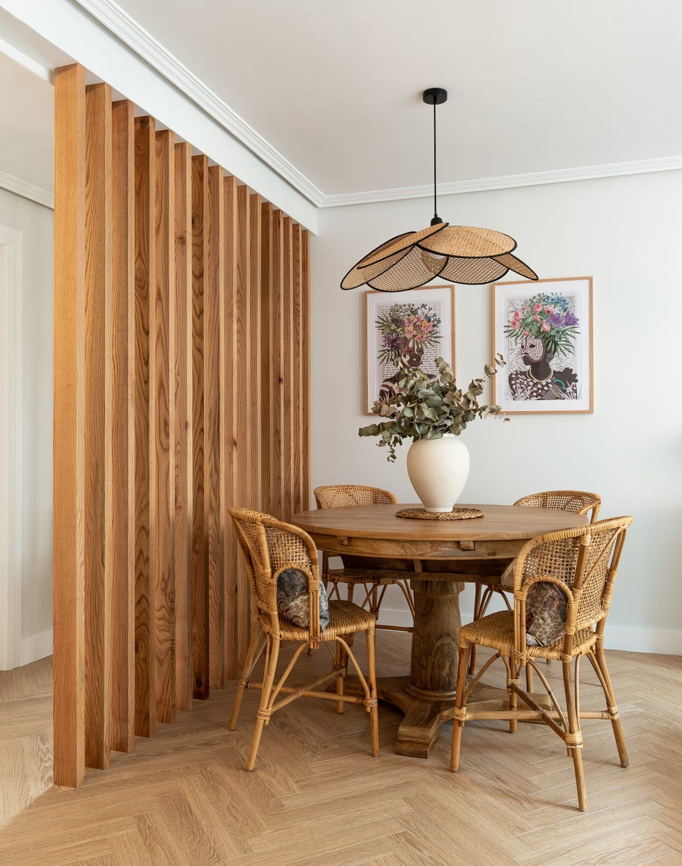 mesa de comedor redonda de madera, sillas de ratán y divisor de ambientes de listones de madera