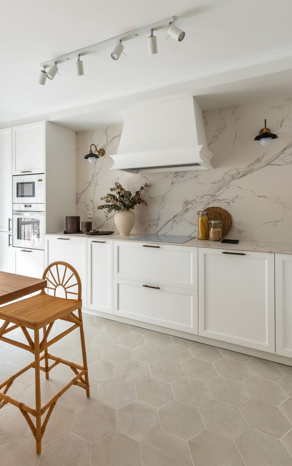 cocina con armarios blancos, encimera y frente efecto mármol y barra de desayunos