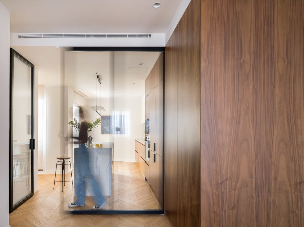 cocina moderna con armarios de madera, isla de mármol y cerramientos de cristal