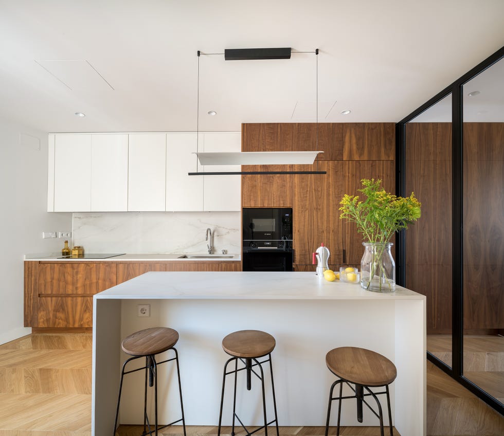 cocina moderna con armarios de madera, isla de mármol y cerramientos de cristal