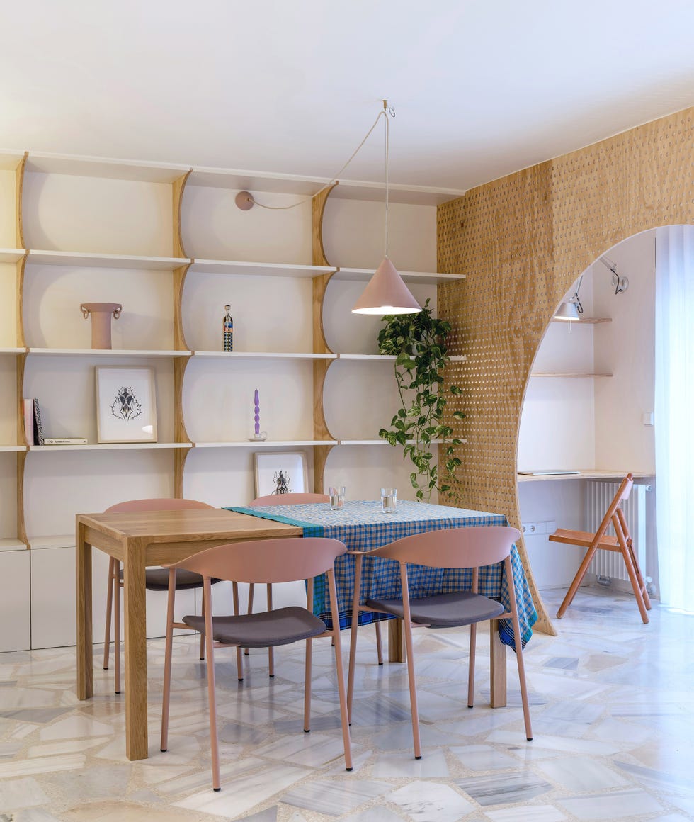 mesa de comedor de madera con sillas rosas y lámpara a juego y estantería de madera