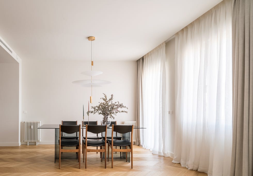comedor con mesa de cristal y sillas de madera y piel negra
