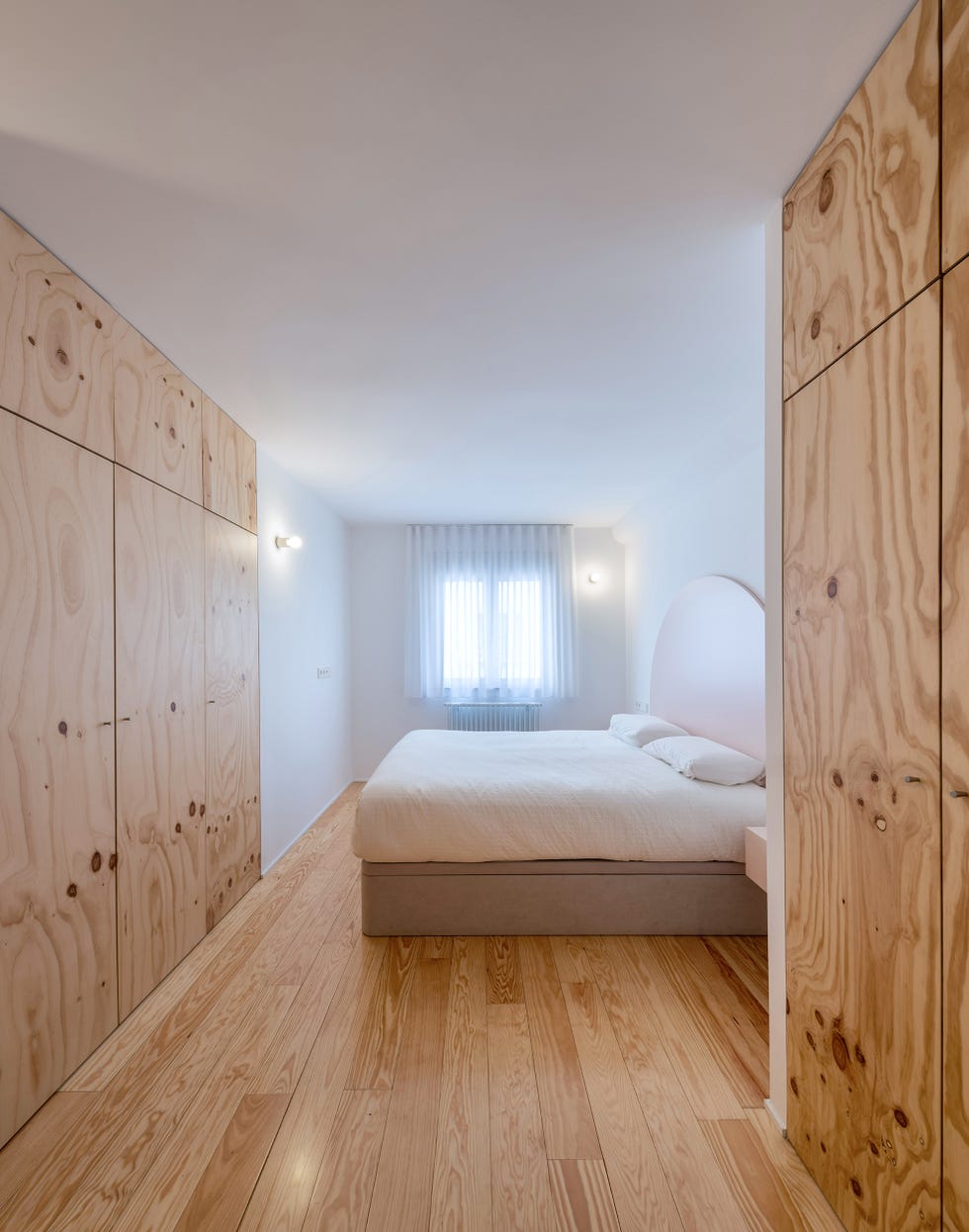 dormitorio con armarios de madera de pino y cabecero en forma de media luna