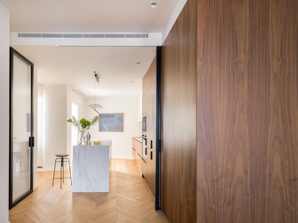 cocina moderna con armarios de madera, isla de mármol y cerramientos de cristal