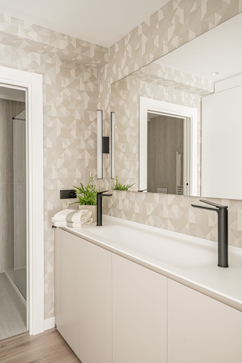baño con mueble beige y papel pintado con motivos geométricos