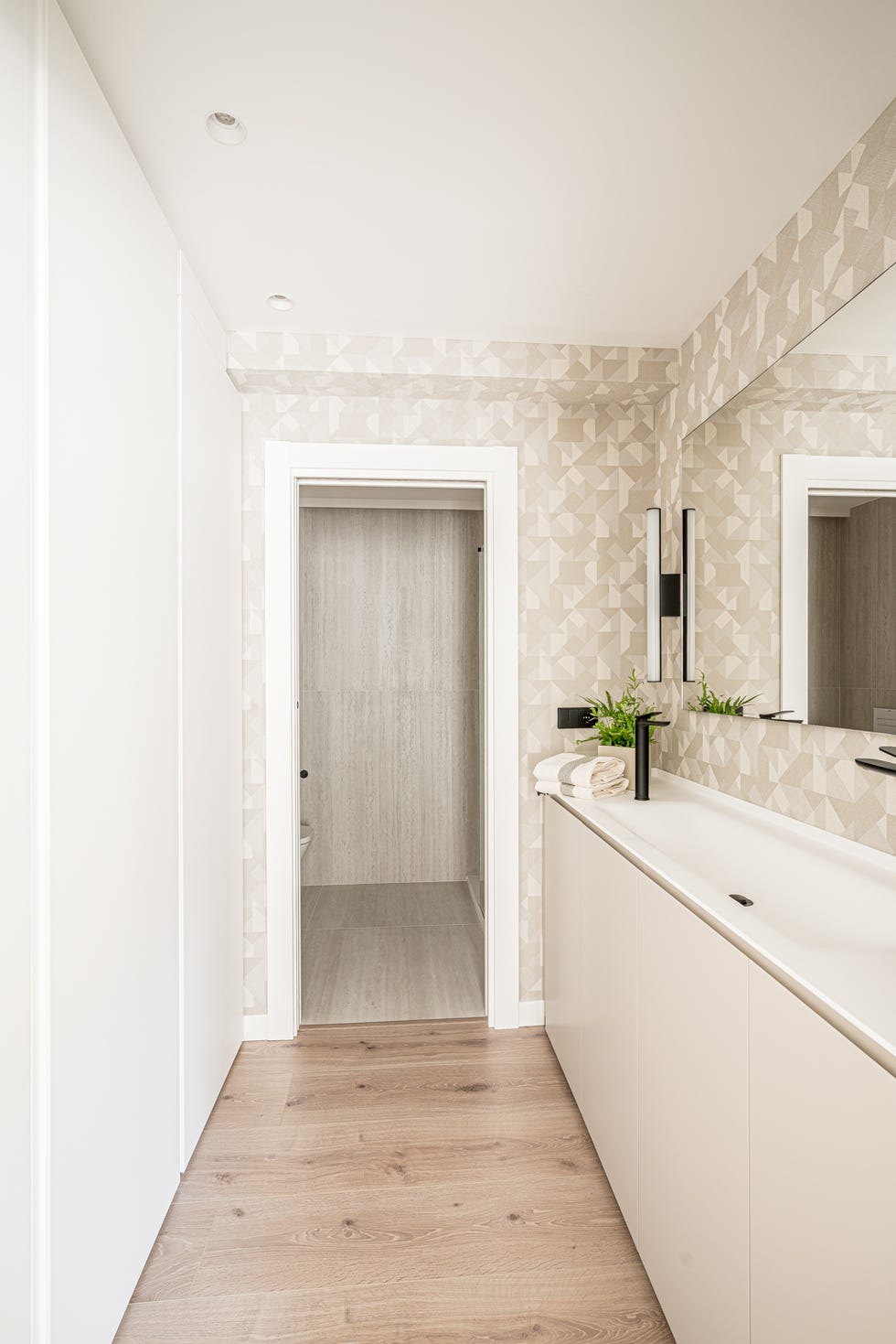 baño con mueble beige y papel pintado con motivos geométricos