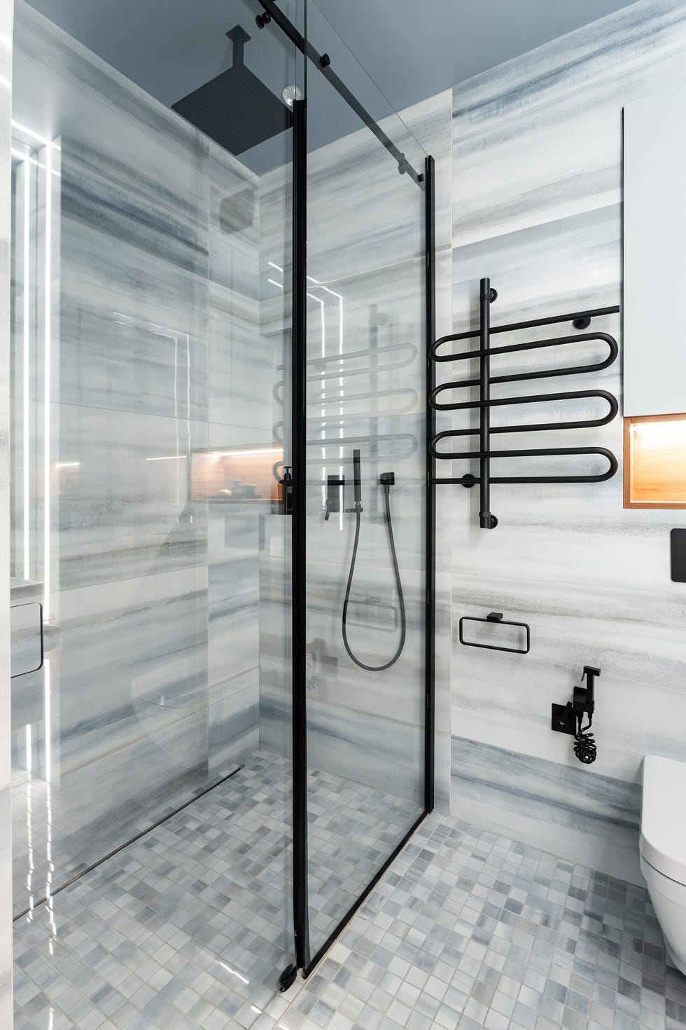 baño moderno con revestimientos de mármol y ducha con mampara fija