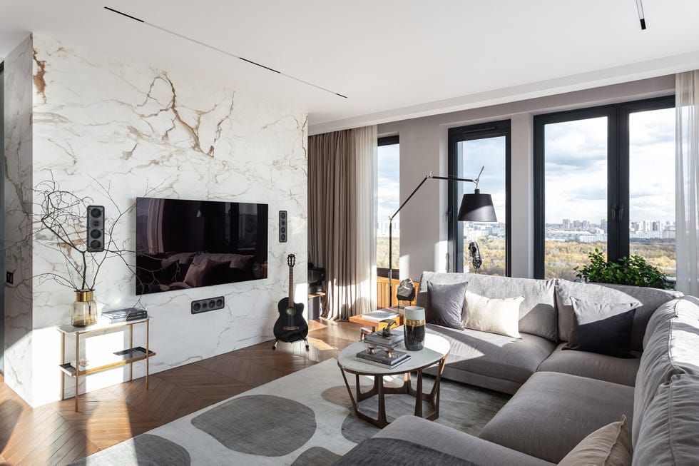 salón moderno con sofá rinconero gris y revestimientos de mármol