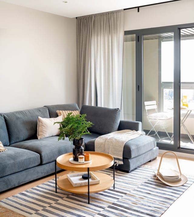 sofá azul con chaiselongue y mesa de centro redonda de madera