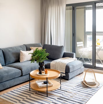 Sofá azul con chaiselongue y mesa de centro redonda de madera sofá azul con chaiselongue y mesa de centro redonda de madera