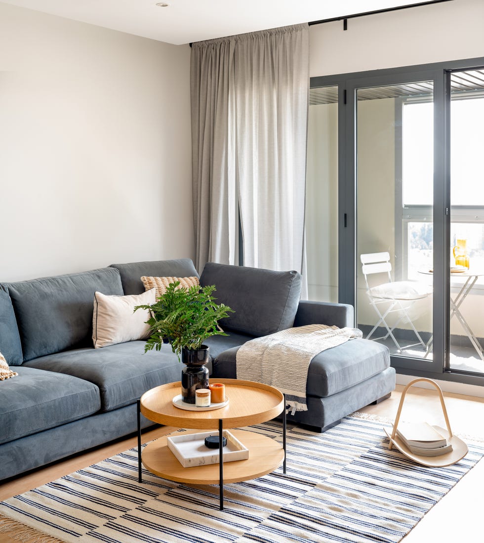 sofá azul con chaiselongue y mesa de centro redonda de madera