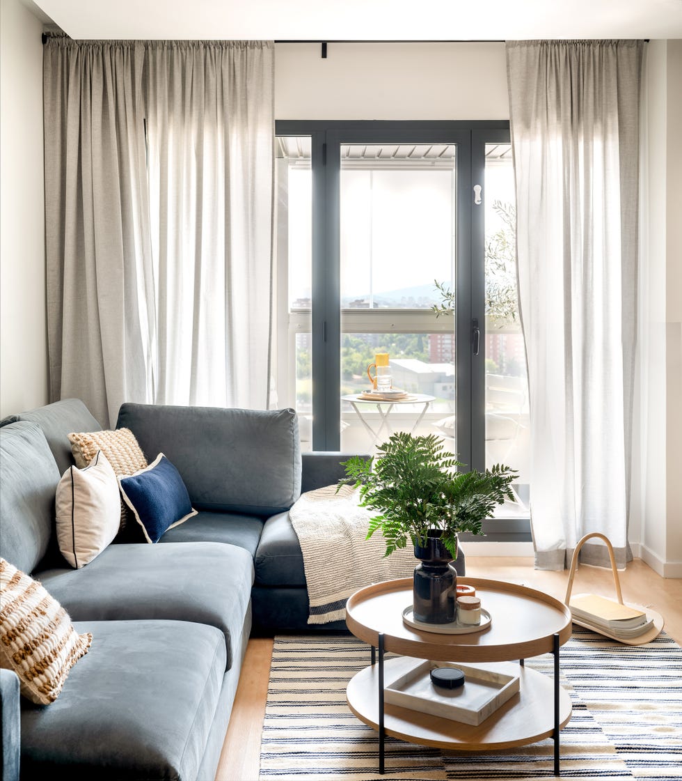 sofá azul con chaiselongue y mesa de centro redonda de madera