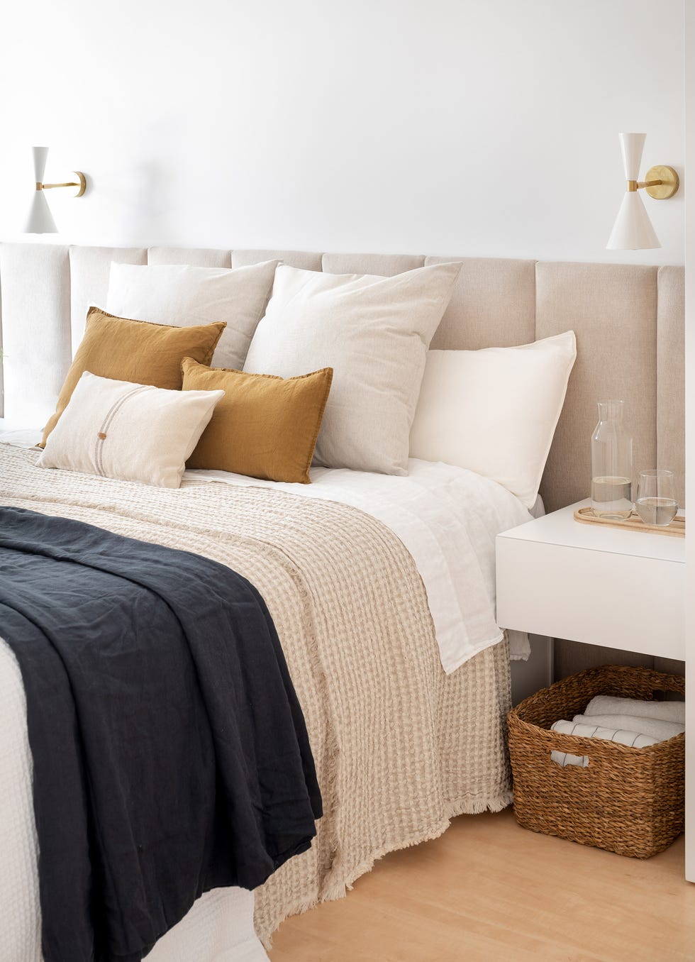 dormitorio con cabecero acolchado beige y mesillas de noche blancas voladas