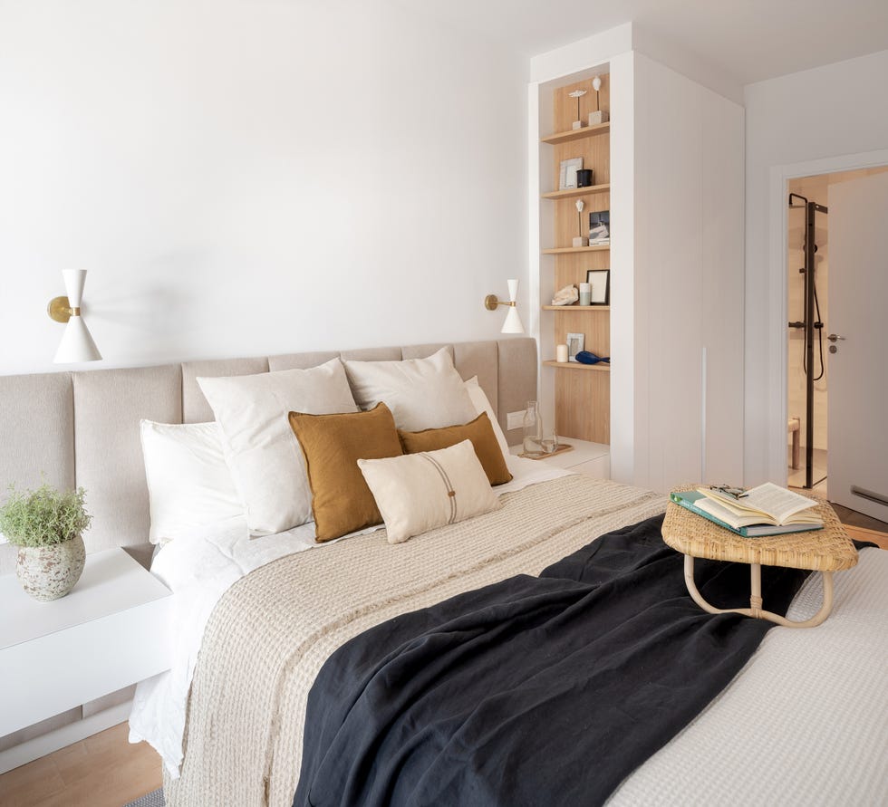 dormitorio con cabecero acolchado beige y estantería de madera