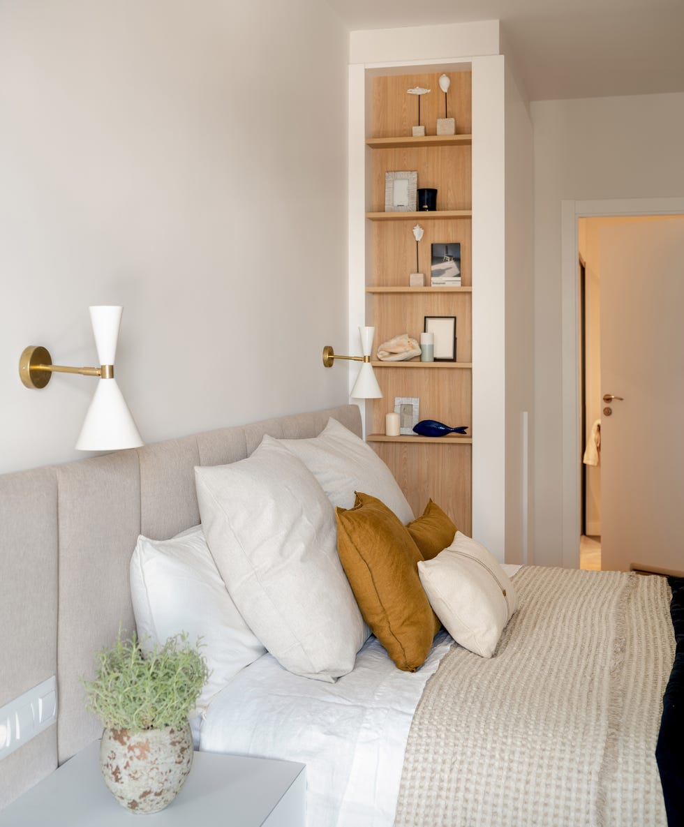 dormitorio con cabecero acolchado beige y estantería de madera