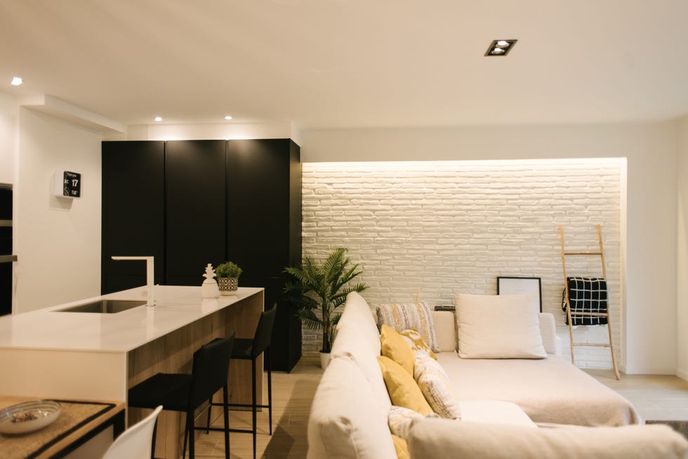 salón de diseño moderno con cocina y pared de ladrillo visto pintada en blanco