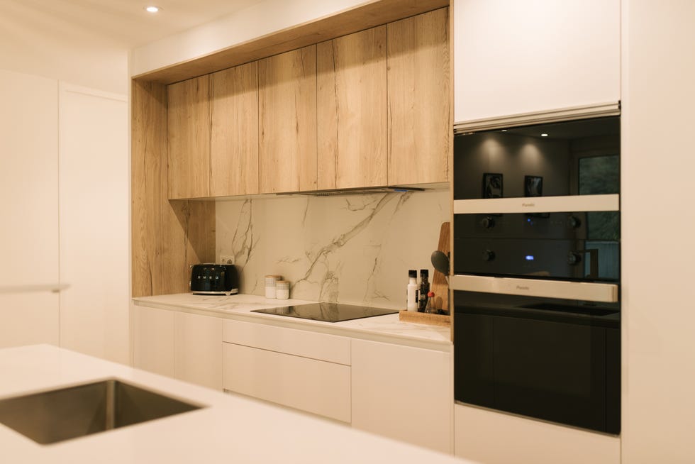 cocina moderna con isla central y revestimientos de mármol y madera