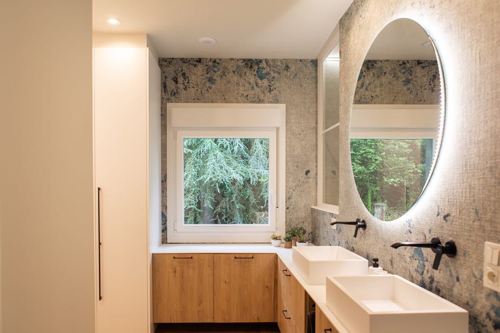 baño con mueble de madera y paredes con papel pintado