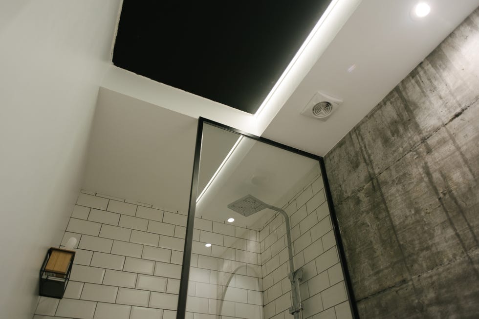 baño moderno con pared de hormigón y ducha con azulejos tipo metro blancos