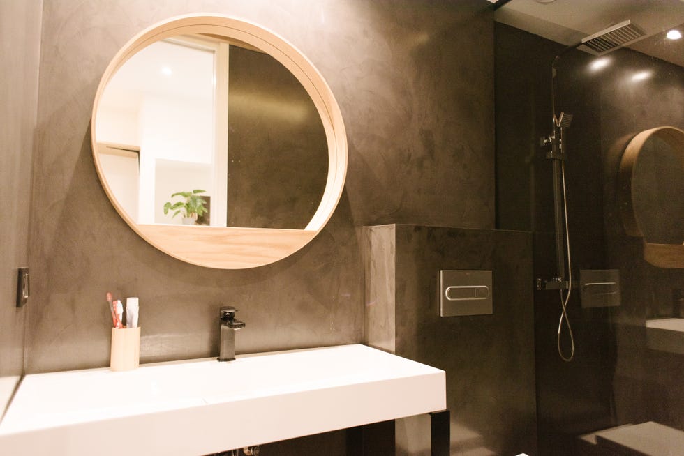 baño moderno con ducha y revestimiento de microcemento gris